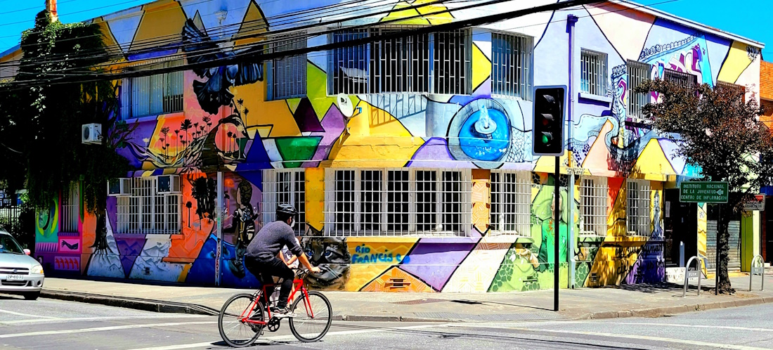 Cyclist crossing the street in front of street art in Chile